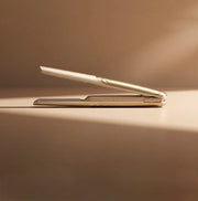 KINU cordless straightener showcased on a softly lit surface, emphasizing its sleek design and portability.